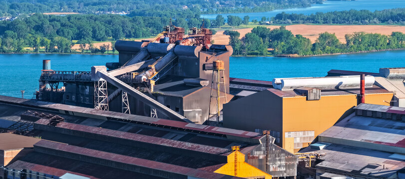 Industrial factory producing by river with green landscape
