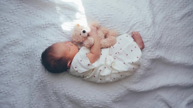 テディベアを抱いて眠る赤ちゃん