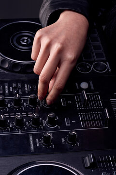 A female DJ's hands displaying and using her turntables in a studio, posing confidently and preparing to dance and play music, wearing a dark, shiny black leather outfit. Retro, nostalgia, technology