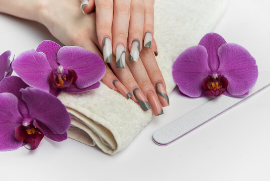 Woman receiving manicure treatment with orchids and nail file