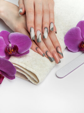 Woman receiving manicure treatment with orchids and nail file