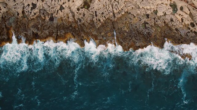 Turbulent sea crashing against uneven coastal rock shelf