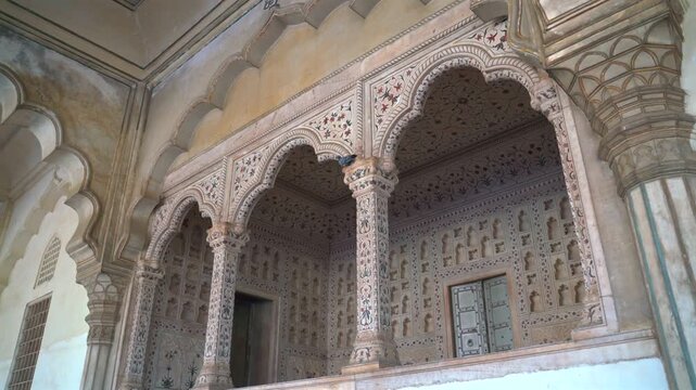 Static low angle shot of decorative cusped white marble arches and floral inlays at the royal Khas Mahal inside Agra Fort, Uttar Pradesh, India.