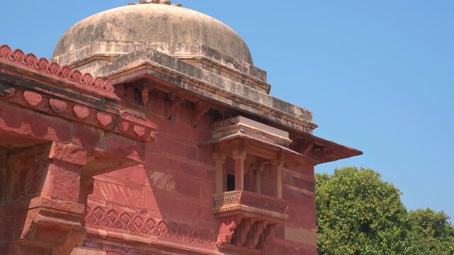 Detailed low angle view of a red sandstone dome and intricate jharokha balcony at Fatehpur Sikri in Uttar Pradesh, India.