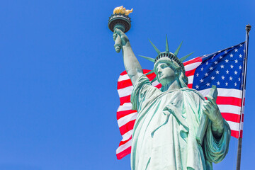 Statue of Liberty with a large american flag and New York skyline in the background © Maria