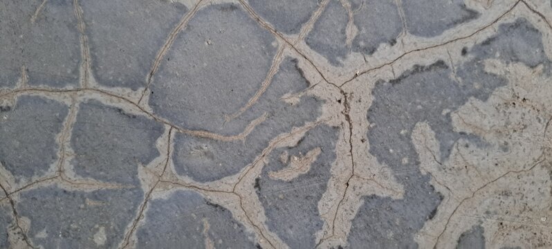 Cracked concrete texture background with fine fracture lines on gray polished cement wall.