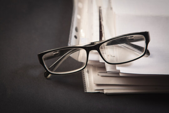 Eyeglasses and documents on a black background.