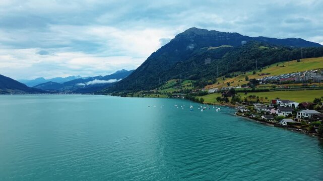 Aerial view of Rigi mountain rising above the turquoise waters of Lake Zug with the village of Arth nestled on the green slopes in Arth, Schwyz, Switzerland.