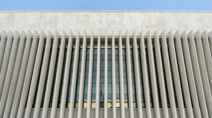 Naklejka premium Modern concrete facade with vertical sunshade fins framing reflective windows