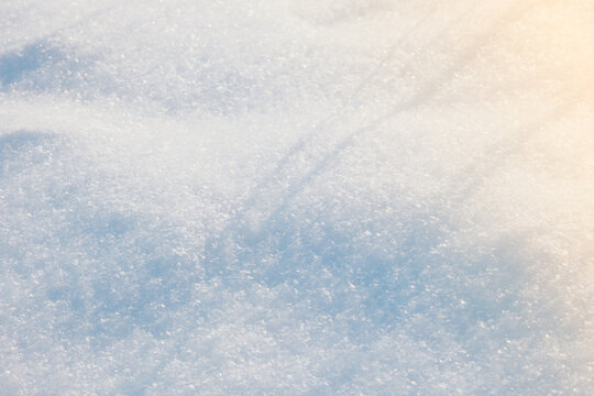 Close up view of clean white sparkling fresh winter snow surface texture glistening under soft warm sunlight