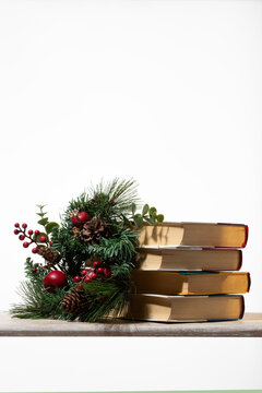 Four classic books stacked beside a rustic Christmas garland. Versatile image for holiday gift ideas, winter break reading lists, and academic seasonal promotions on clean white space.