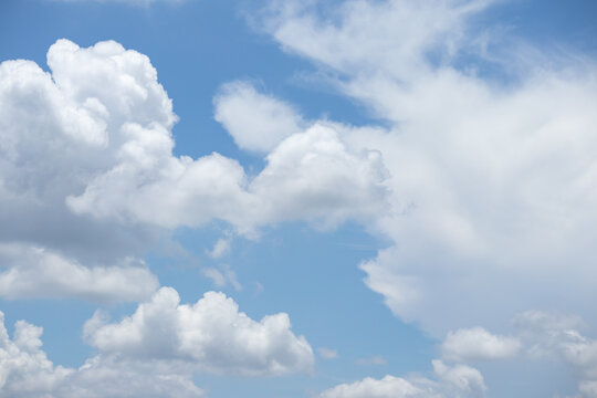 fluffy white clouds building up in the light blue sky