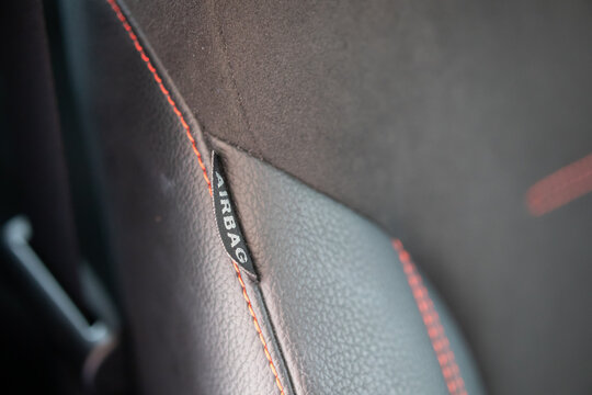 Airbag Label Tag on Black Leather Car Seat with Red Stitching