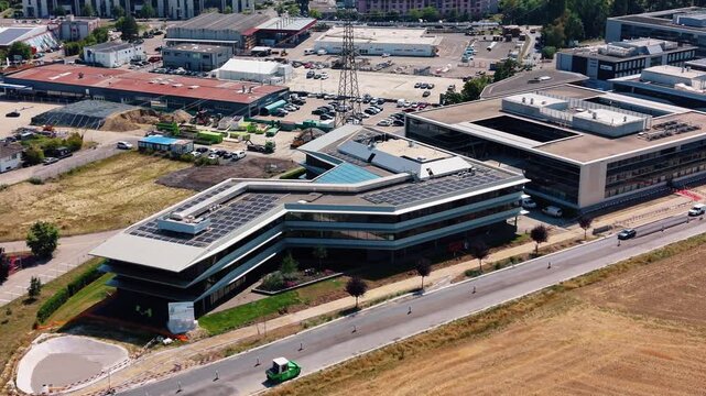 Aerial view of modern office building with solar panels on the roof at Rte de Crassier 11 in Eysins, Vaud, Switzerland.