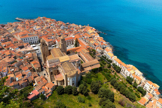 Aerial view of an ancient European coastal town with terracotta roofs and a prominent church