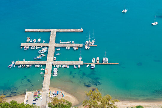 Aerial view of a modern geometric pier filled with yachts and boats in clear blue water