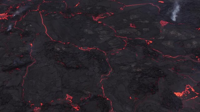 Aerial view of glowing magma flowing through cooling black basalt rock formations in Reykjavik, Reykjavikurborg, Iceland.
