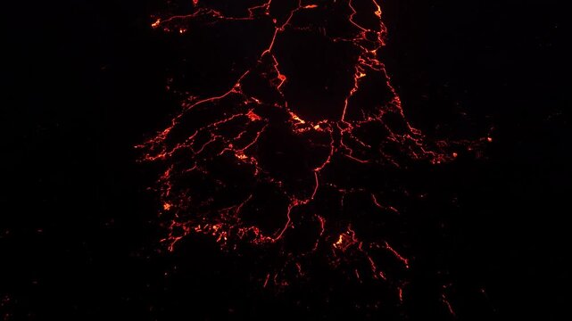 Aerial view of glowing lava flows at night with bright magma patterns across the dark volcanic landscape in Reykjavik, Reykjavikurborg, Iceland.