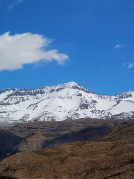 mountain and clouds. Defocused view of snow-capped peaks rise above rugged alpine terrain, contrasting barren foreground with majestic mountain beauty under partly cloudy skies. Summer background 