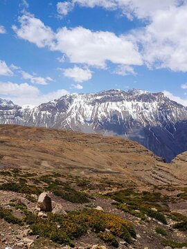 high mountain landscape. Defocused view of snow-capped peaks rise above rugged alpine terrain, contrasting barren foreground with majestic mountain beauty under partly cloudy skies. Summer background 