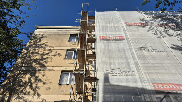 A multi-story building under renovation with scaffolding and protective mesh covers on a clear day. Picture taken on September 1, 2026 in Bucharest, Romania.