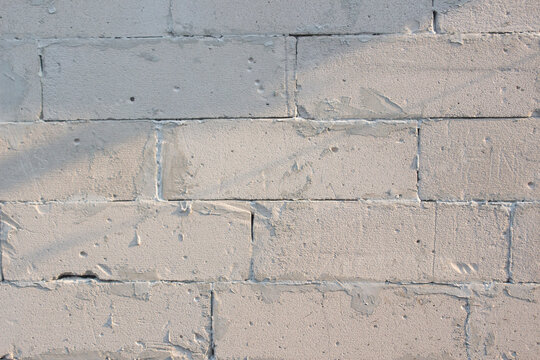 Light grey lightweight concrete block wall texture with cement mortar lines and rough masonry background