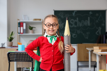 Education and academic success, little girl dressed as a superhero holding a giant pencil in a...