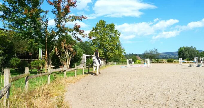 Beautiful young female rider trotting on her horse 