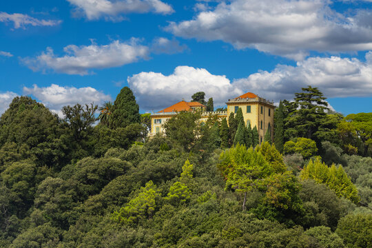 Scenic view of a traditional villa on a wooded hillside in Italy with dramatic clouds