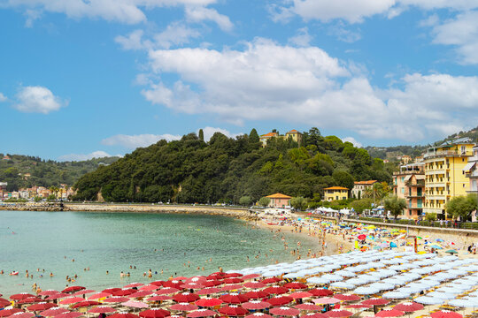 Scenic bay view featuring a sandy beach, colorful umbrellas, and lush green hills