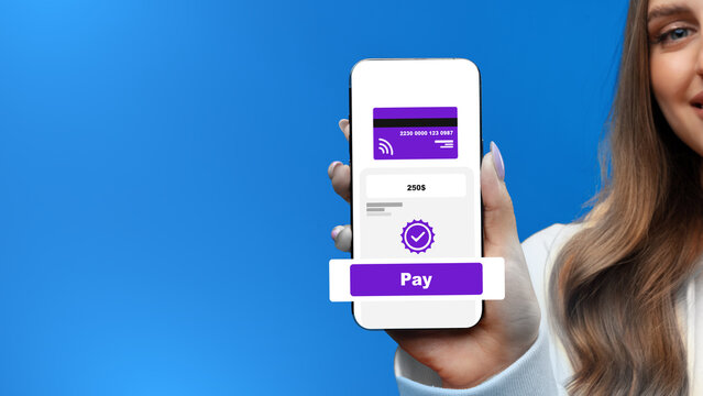 Holding a phone showing online payment process with a visible pay button on a blue background