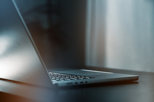 Lifting the lid on a laptop resting on a wooden table in a well-lit room during the day