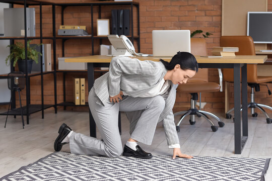 Young businesswoman suffering from severe abdominal pain in office