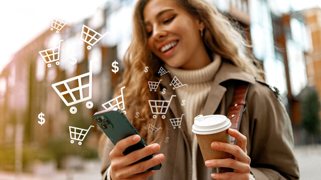 Woman shopping online with smartphone while holding coffee cup on city street in daytime