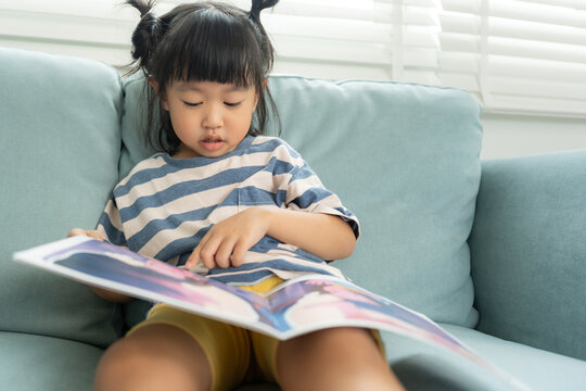 Happy Asian children relax read book at home. daughter and reading a story. learn development, childcare, laughing, education, storytelling, practice, imagine, reduce addiction mobile phone