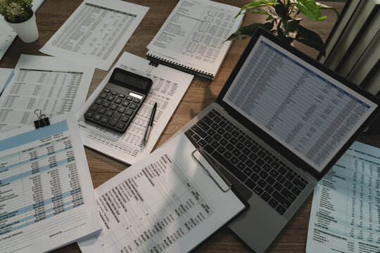 Budget planning workspace with laptop spreadsheet, calculator and printed financial reports for financial data analysis, financial planning and expense management.