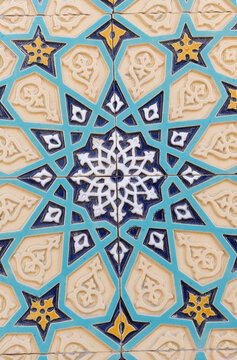 closeup of a traditional uzbek ceramic tile mosaic with a turquoise geometric background, relief motifs, blue star shapes and golden floral details, creating a symmetrical ornamental architecture
