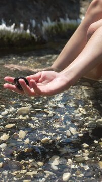 Hand rock water, close up of a woman holding a stone over a clear ocean shoreline for summer travel and vacation concept