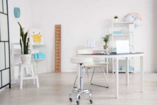 Blurred view of pediatricians office with workplace and stadiometer