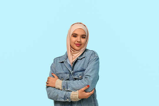 Beautiful young Muslim woman in hijab on blue background