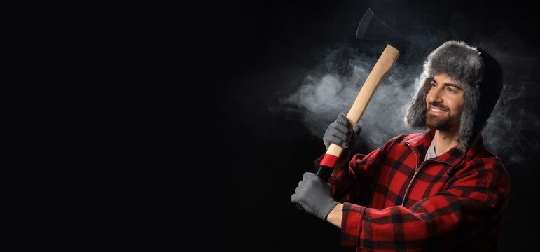 Rugged masculinity and winter survival, smiling lumberjack holding an axe in cold weather with smoke and dark background
