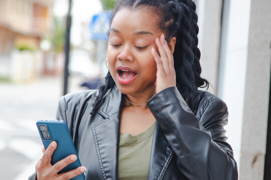 woman on the street making a face of surprise or amazement when she reads a message on her mobile phone