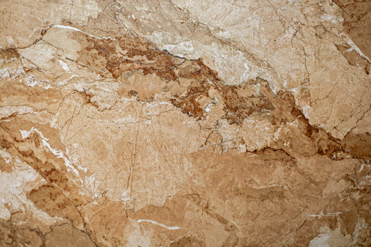 Brown and Beige Marble Stone Texture. Close-up of brown and beige marble with natural veining, mottled mineral patterns, fine cracks, and polished stone texture.