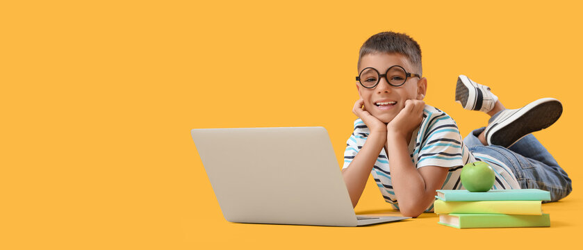 Remote learning and digital education, happy school boy using laptop for online classes with books and apple on a bright yellow background
