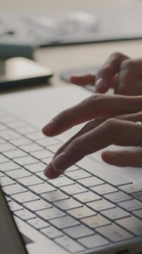 Close-up of female hands typing with laptop computer while businesswoman working at desk in office. Modern technology and business concept.