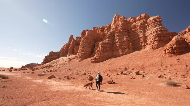 Young Woman and Dog on Leash on Hiking Trail in Desert Landscape of Goblin Valley State Park, Utah USA