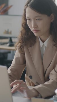 Asian business lady using laptop computer typing working at desk in modern office. Professional occupation and modern technology concept.