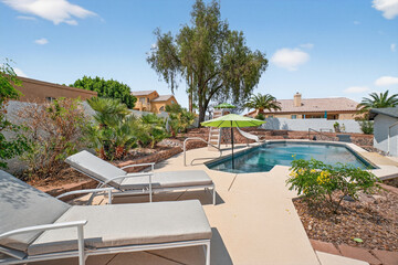 Fototapeta premium Poolside patio with lounge chairs and umbrella