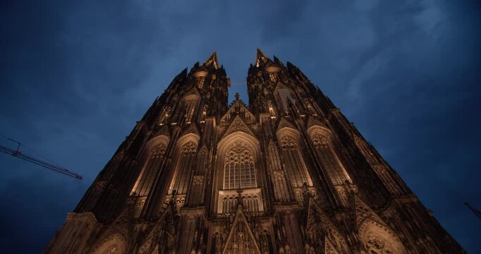 Gothic architecture Cologne Cathedral Germany night cityscape shows a magnificent historic church surrounded by illuminated urban streets in a popular European tourist city.