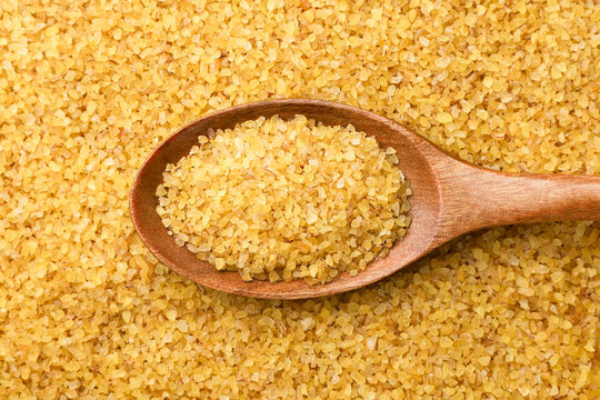 Bulgur groats in a wooden spoon background. Top view